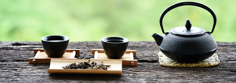 Japanese iron teapot with two cups on a dark wood table