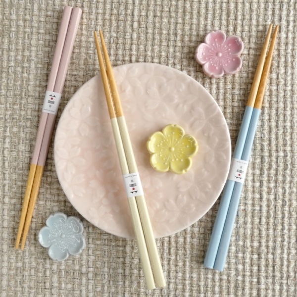 Pastel chopstick and chopstick rest sets in pastel pink, yellow and blue on a table with pale pink plate
